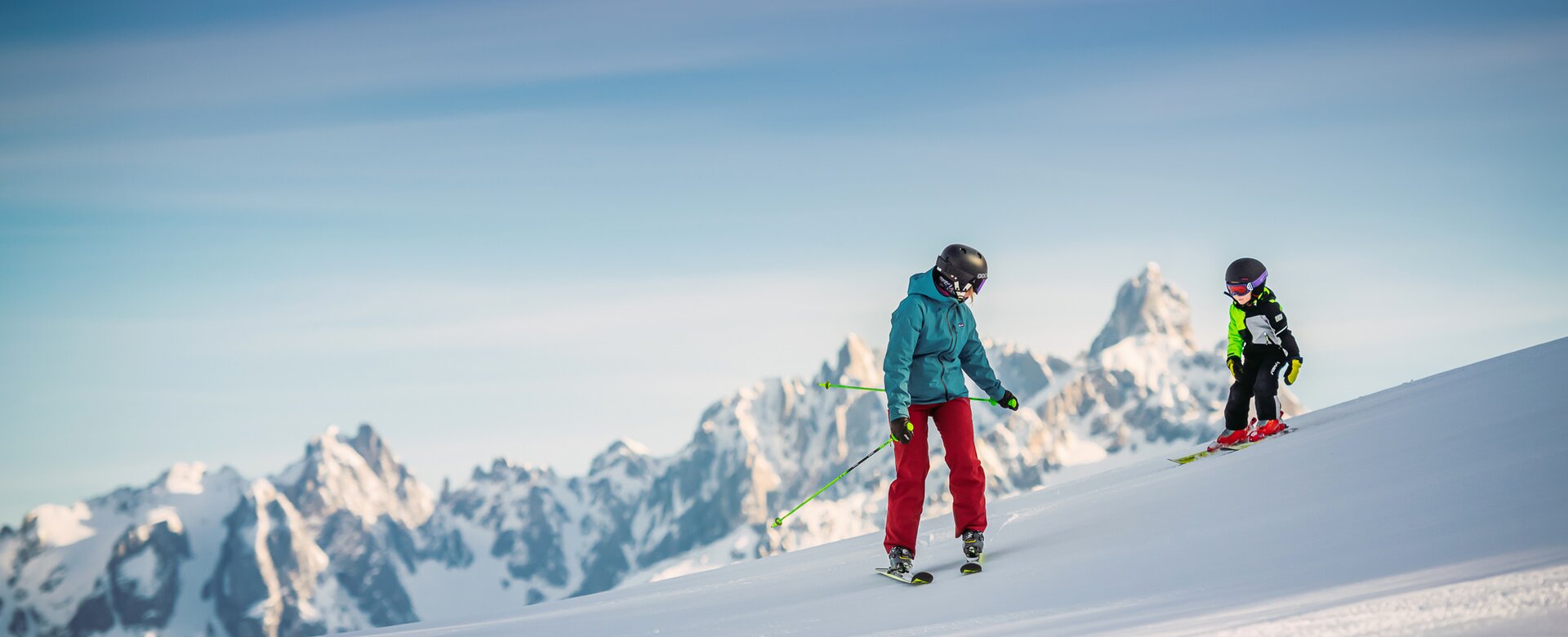 A child with rides with his dad in front of a mountain peak on freshly groomed piste. | © Snow Space Salzburg