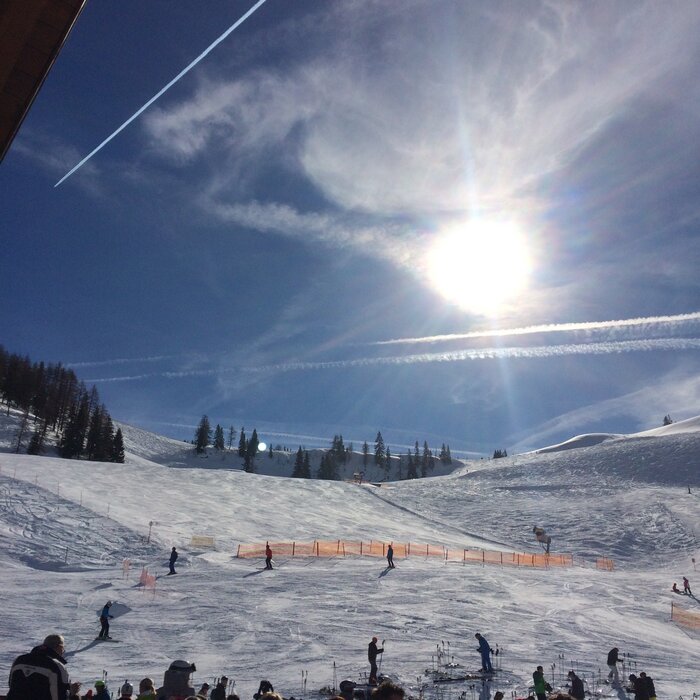 Skiers enjoy a sunny spring day on the snow-covered slopes. | © Anna Pilz