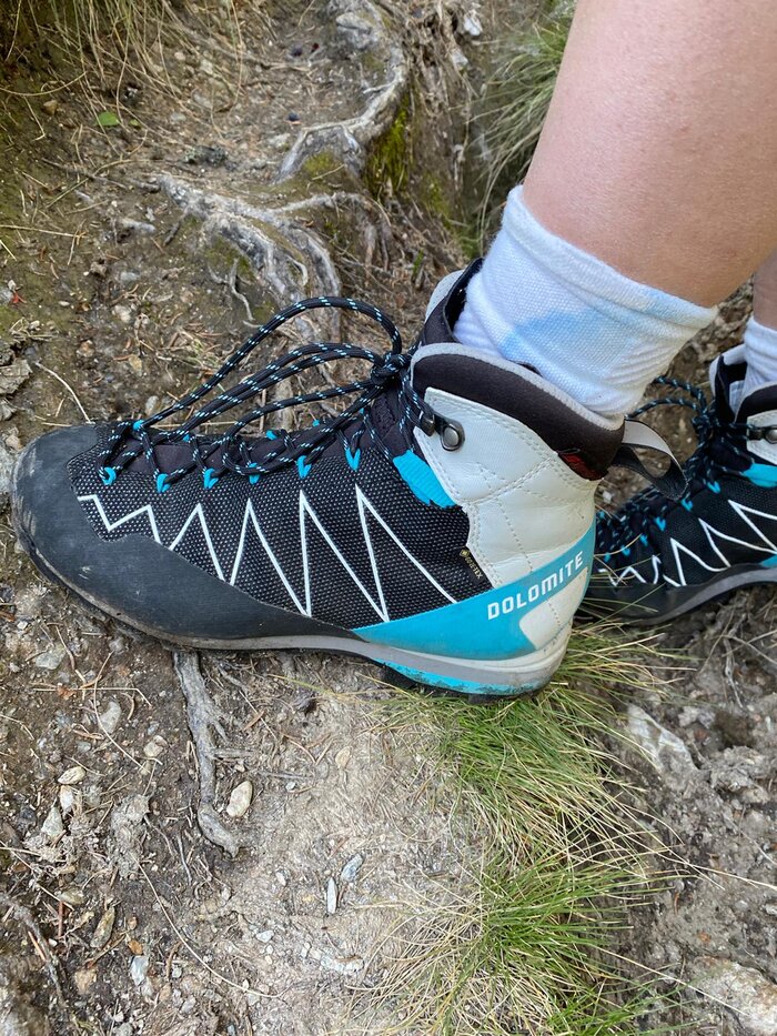 Close-up of a Dolomite hiking boot on a rooty, rocky trail – symbol of secure footing and proper gear in alpine terrain.