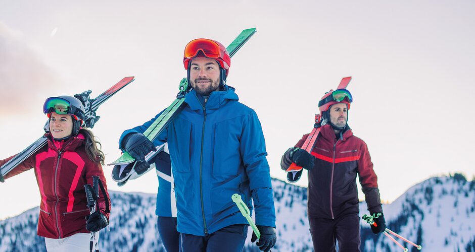 Four skiers carrying their skis on their shoulders – the perfect start for the Back2Ski course, a program for returning skiers. | © Ski amadé