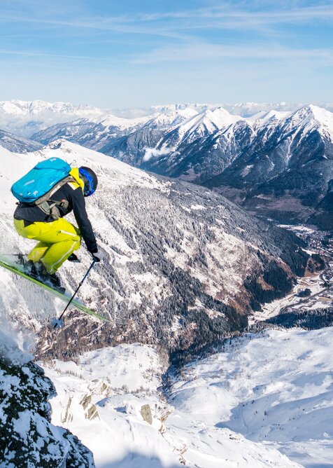 Skier with backpack jumps over a cliff and you can see into the mountain-lined Gastein Valley | © www.oberschneider