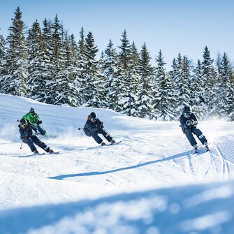 Four young skiers with helmets racing dynamically on snowy Funcross course at Shuttleberg resort | © Shuttleberg