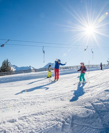 Family skiing down a hill slope with a platter lift in the background | © Tourismusverband Großarltal