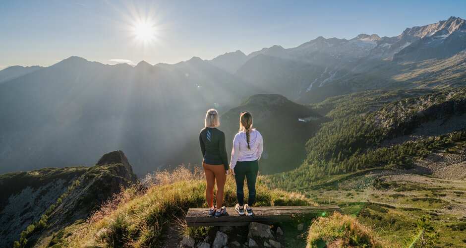 Two women enjoy the sunrise view from Graukogel overlooking Gastein Valley and the surrounding mountain peaks | © Skigastein, seven frames