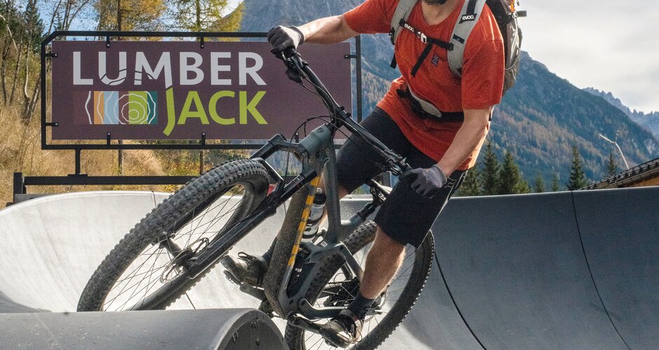 A mountain biker rides over a wave on the paved pump track in front of the Lumberjack. | © Shuttleberg