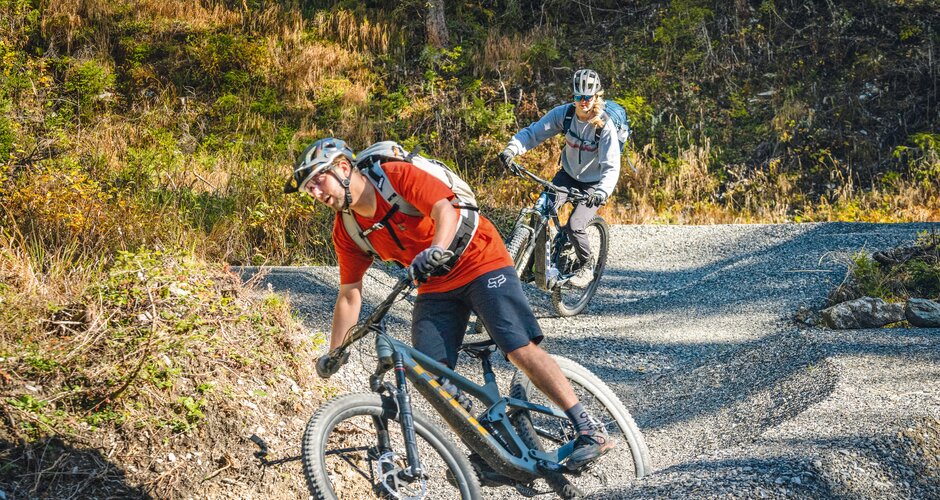 Two mountain bikers cornering on a gravel pump trail with strong lean angles. | © Shuttleberg