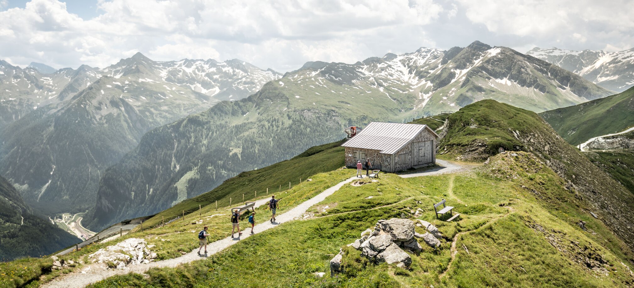 Group of hikers on mountain trail near wooden hut with view of snow-covered peaks in Gastein | © Gasteinertal Tourismus GmbH