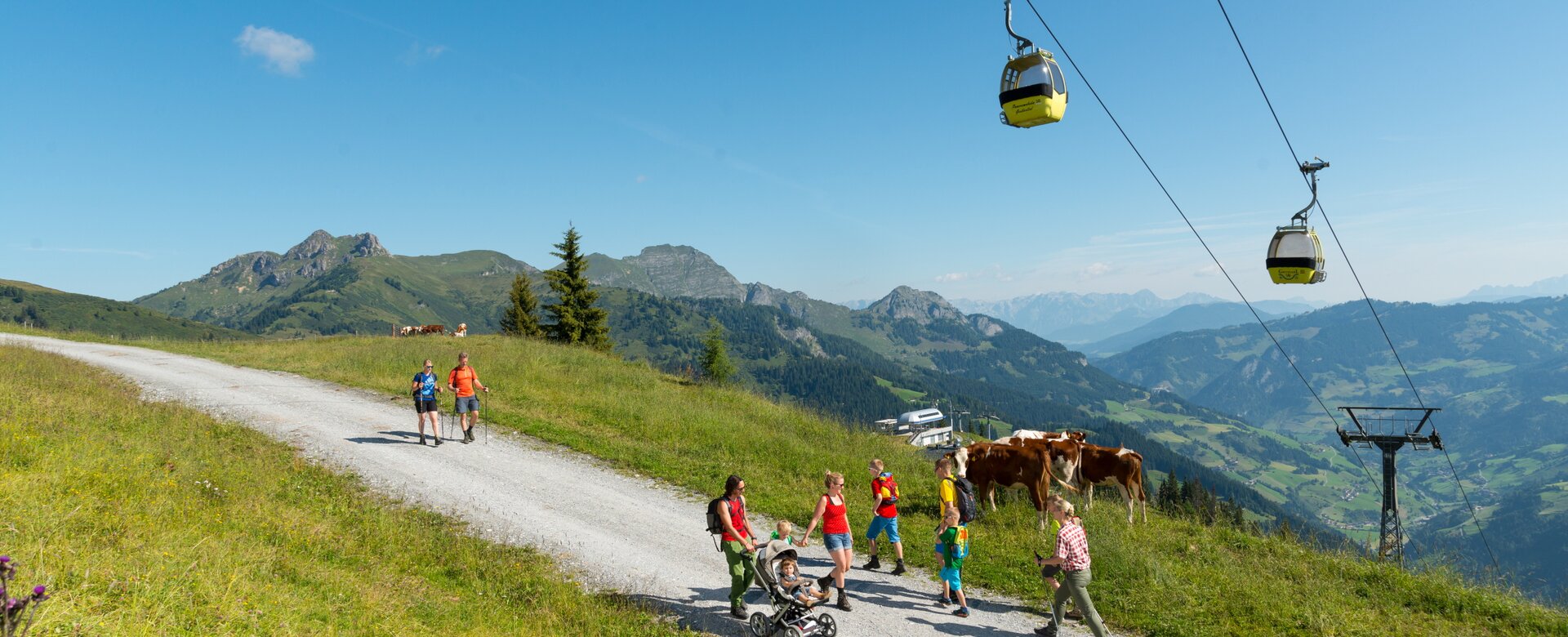 People walk up the mountain on a gravel road under a cable car | © Gruber Michael