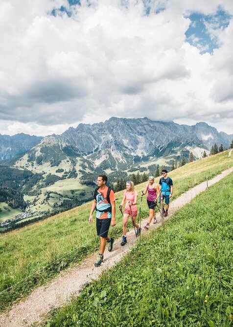 Five hikers walk along mountain path above green valley with panoramic view of the rugged Hochkönig massif in the background | © Hochkönig Tourismus GmbH