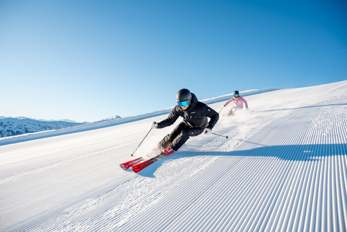 Two skiers on perfectly groomed pistes in glorious sunshine in the Hochkönig ski region near Maria Alm - pure winter fun and nature experience.  | © Hochkönig Tourismus GmbH