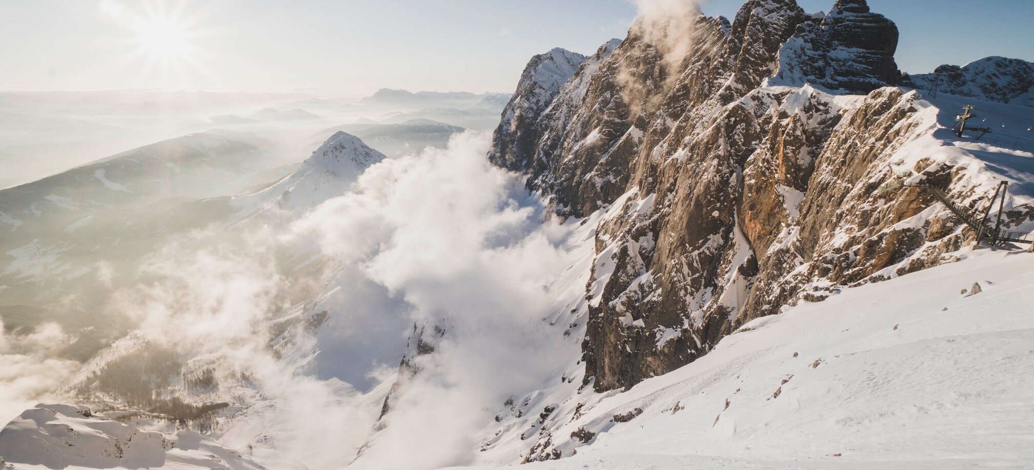 Snowy mountains with clouds and rocky walls, sunrise at Dachstein. | © David McConaghy