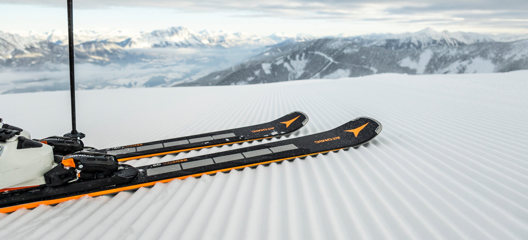Close-up of skis on a freshly groomed slope with mountain views. | © Mirja Geh