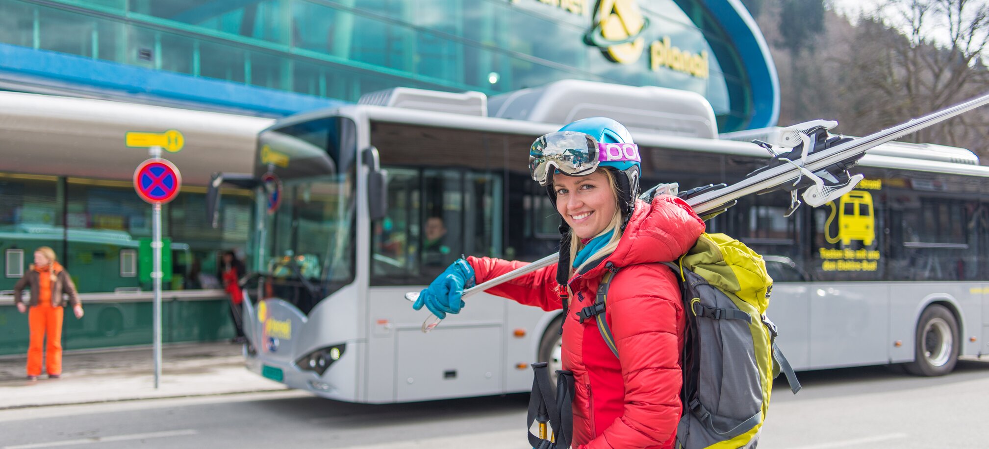 Frau mit Skiern und Rucksack vor Skibus an der Haltestelle in Schladming-Planai. | © Christine Höflehner