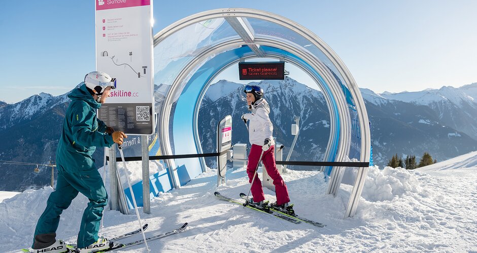 A couple on skis stands in front of the start of a skimovie track and talks | © Gasteiner Bergbahnen AG, Wolkersdorfer