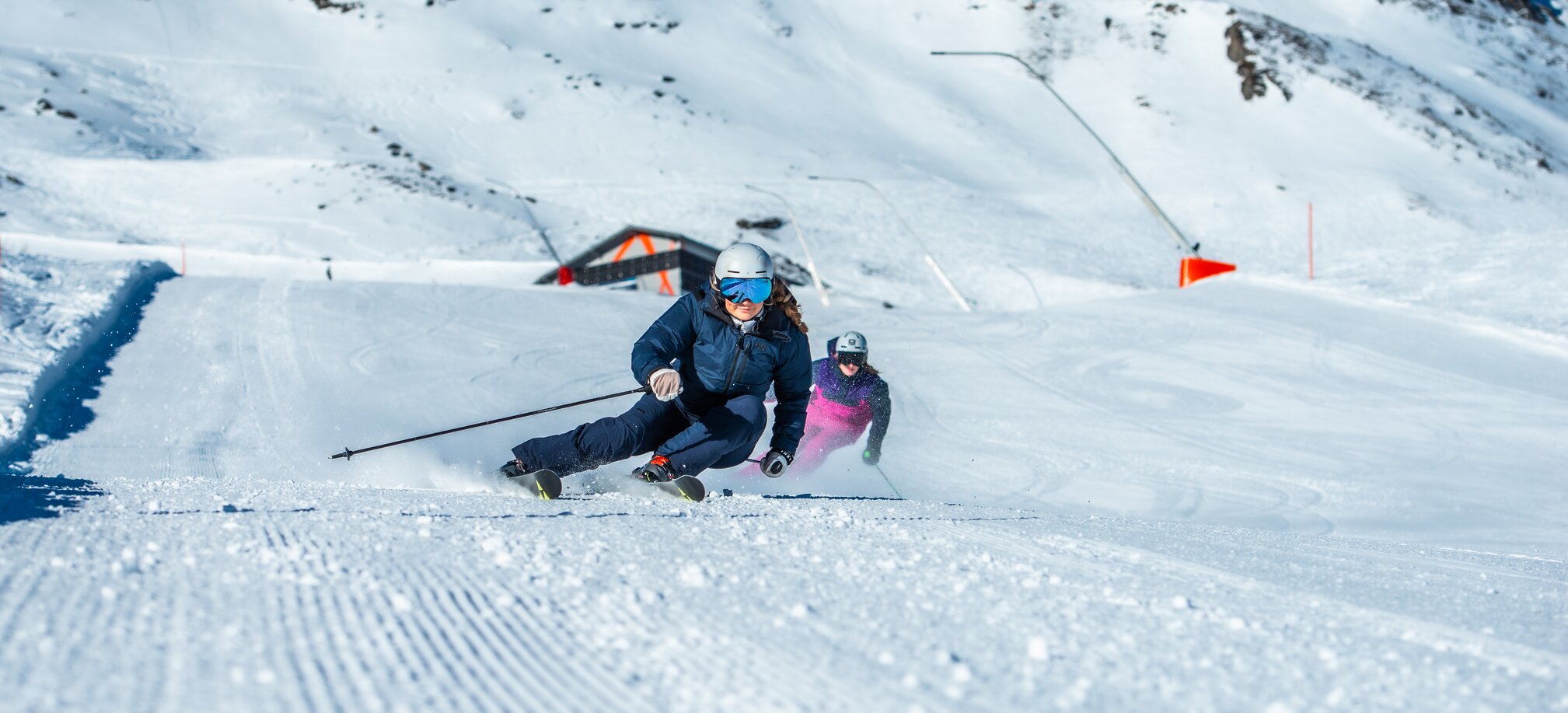Two skiers descend a groomed slope in Skigastein on a sunny day | © Max Steinbauer