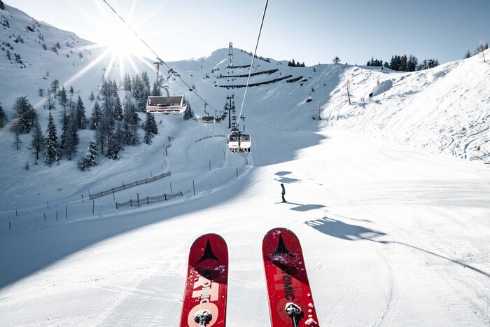 St. Johann – Alpendorf ski area with chairlift, snowy slopes, skiers and mountains