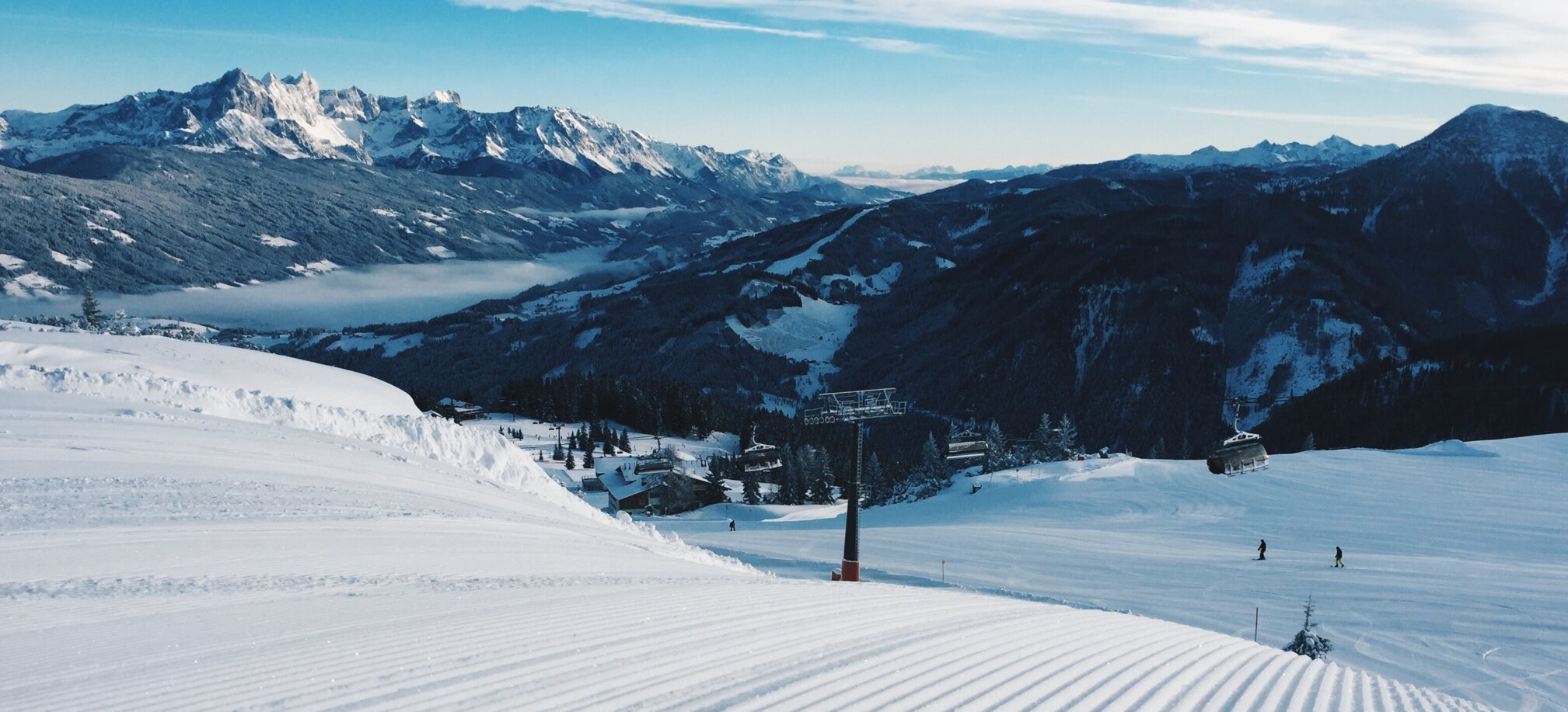 Freshly groomed ski slope with a chairlift and snowy mountains. | © Ski amadé