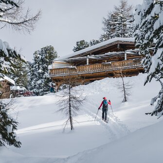 Ski tourer approaches Graukogelhütte on snowy slope through forested winter landscape | © Gasteinertal Tourismus GmbH, Christoph Oberschneider