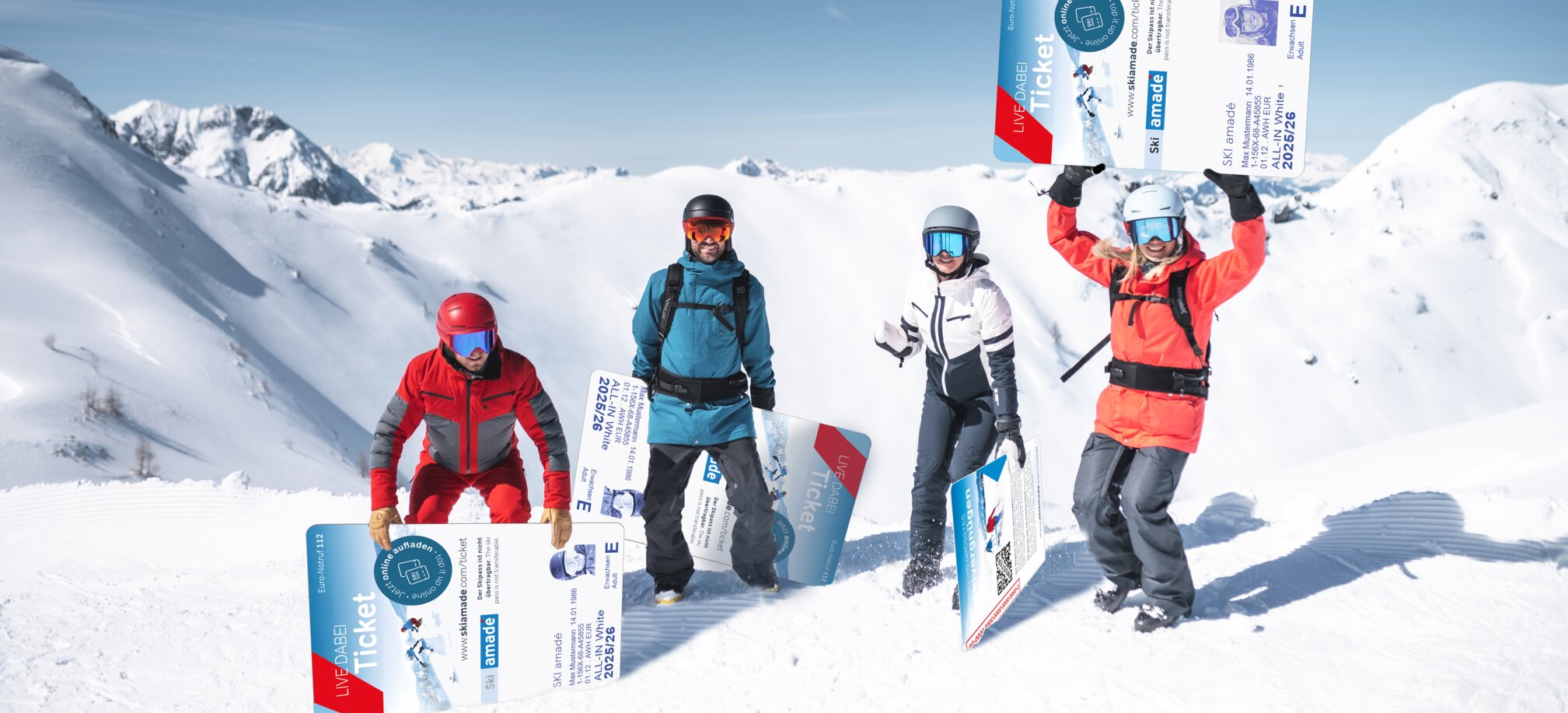 Four winter sports enthusiasts pose with giant ski passes in the snow before alpine mountain scenery.